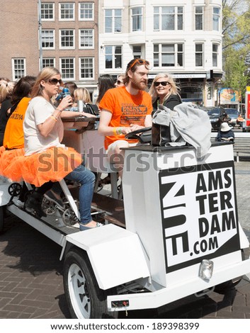 AMSTERDAM - APRIL 26: Unidentified cyclists ride beer bike through the city streets on King's Day, Dutch annual national holiday, on April 26, 2014 in Amsterdam, The Netherlands
