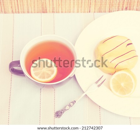 Cup of tea with slice of lemon and yellow cake with lemon flavored icing. Toned image in a nostalgic retro style.