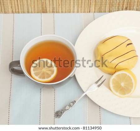 Cup of tea with slice of lemon and yellow cake with lemon flavored icing
