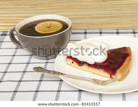 Cup of black coffee with slice of lemon and fruit jelly cake with meringue topping