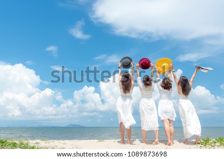 Smiling group woman wearing fashion white dress summer walking on the sandy ocean beach, beautiful blue sky background.  Happy woman enjoy and relax vacation. Lifestyle and Travel Concept