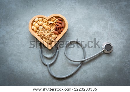 Healthy Foods. Mixed nuts in heart shape and stethoscope with nuts for diet on a concrete background. Different kinds of tasty and healthy nuts. Top view and copy space.  Healthy Concept