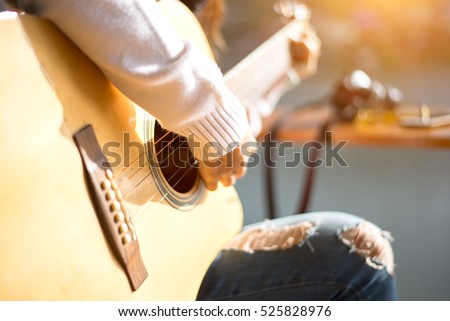 woman\'s hands playing acoustic guitar, close up, soft and select focus