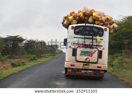 OMO VALLEY, ETHIOPIA - NOVEMBER 26, 2011: Overloaded bus moves on the road through the african village in Ethiopia.