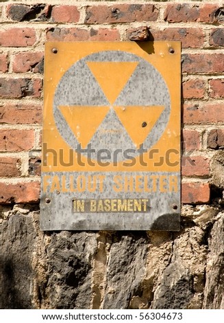 Faded fallout shelter sign on brick