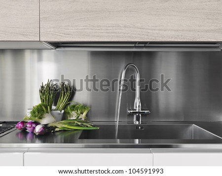 detail of vegetables near to steel faucet in a modern kitchen