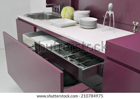 close-up of open red furniture in the modern kitchen with dishes on the worktop