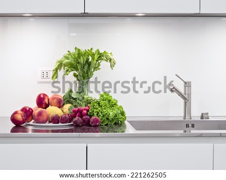 fruits and vegetables on the steel worktop near to sink in the modern kitchen