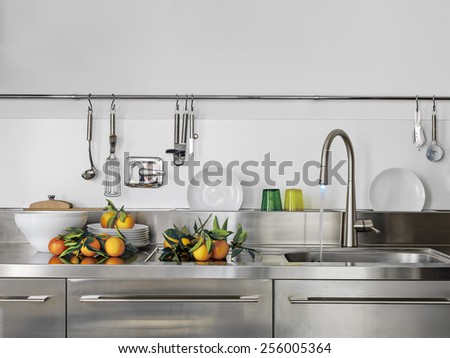 detail of sink and faucet in the modern kitchen with orange on the worktop