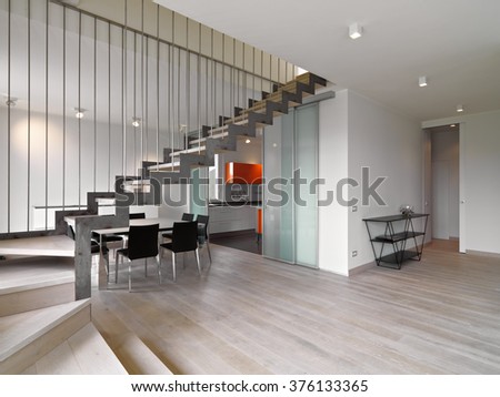 foreground of iron staircase in te modern living room overlooking on the dining room and the kitchen whose floor is made of wood