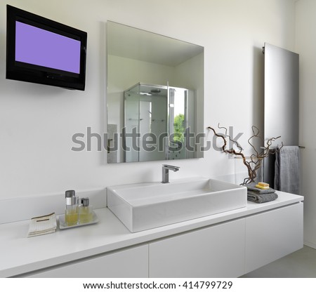 detail of washbasin in a modern bathroom with television and large mirror