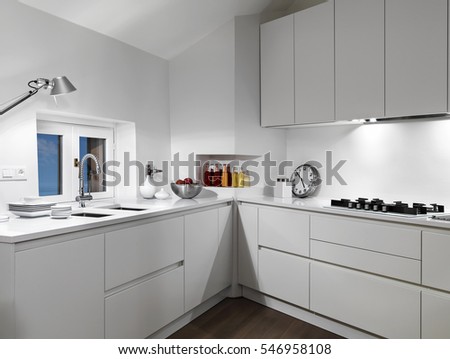 interior view of a white  modern kitchen in the mansard with wood floor