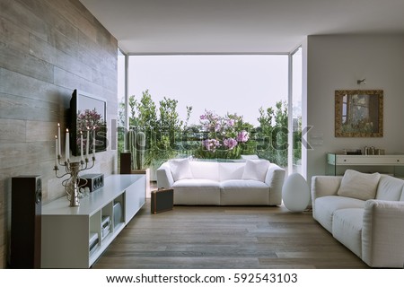interior view of a modern living room overlooking on the terrace with white fabric couch and wooden flooring