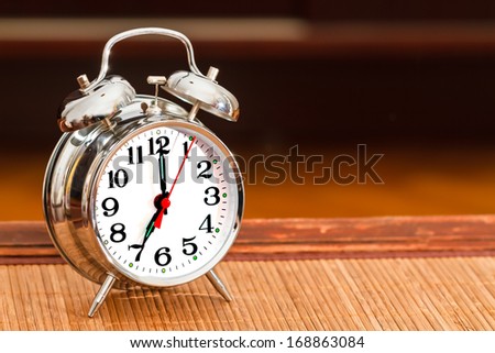 Retro silver alarm clock showing time as seven o\'clock.