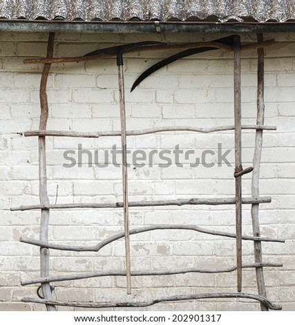 rake and scythe hanging on the ladder for the creeper plant