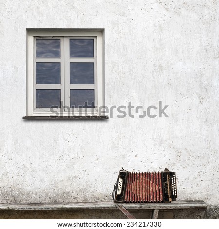 accordion on the bench near the wall with a window background
