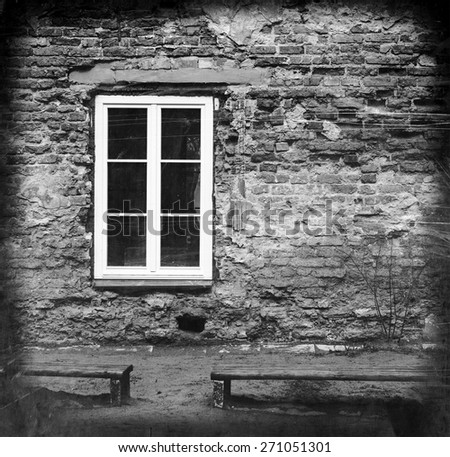 grunge brick wall with a window and two benches, black and white image