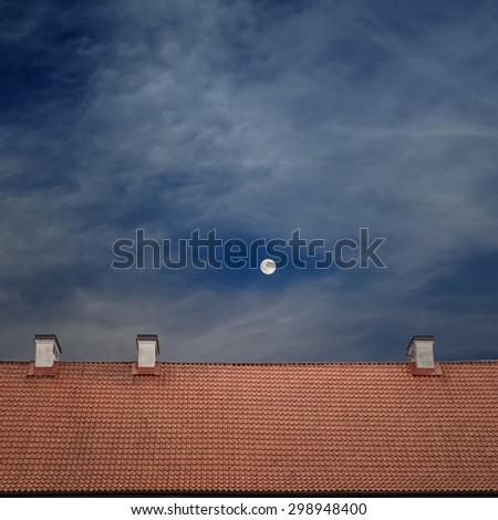 tiled top of the roof, cloudy blue sky and the moon at night
