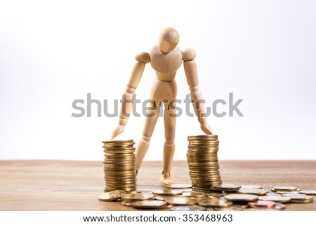 A wooden doll man with his savings, gold coin. All composed with thai baht twenty-five and fifty cent