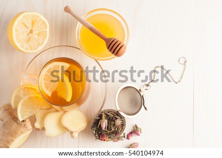 Closeup of cup of tea with tea leaves, mint on vintage wooden background. Black herbal tea with lemon, ginger and honey. hot winter drink