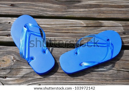 Child\'s blue flip flops sitting on a boardwalk