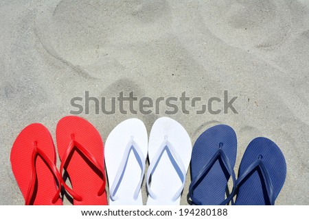 Red white and blue flip flops on the sand. Plenty of room for your text
