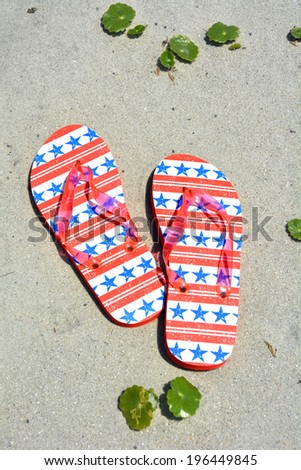 Red white and blue flip flops on the sand. Perfect for cover art