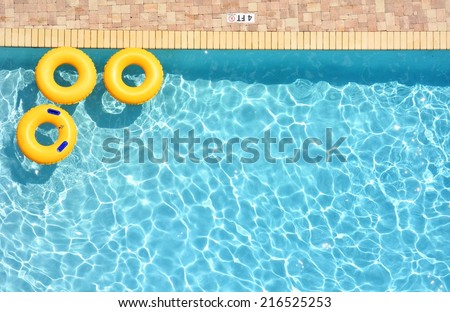 Three yellow pool rings floating in a swimming pool, room for your text