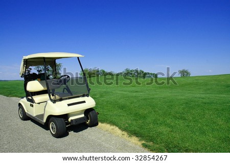 Golf cart on path, pretty green grass and blue sky background room for copy space