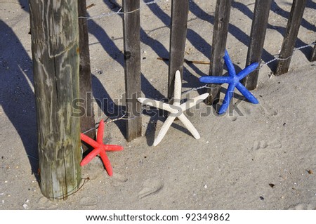 Red, White and Blue Starfish sitting by beach fence. Room for your text