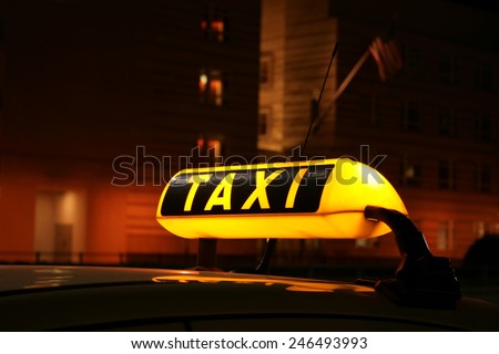 Illuminated TAXI sign on car cab waiting for a fare in the city at night, seen in front of the Berlin US Embassy