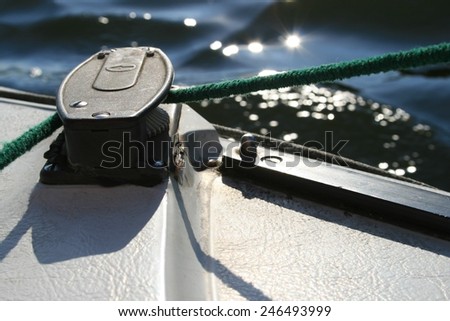 On deck of a sailing boat a green rope is pulled around a idler pulley as commonly used to tighten a sail