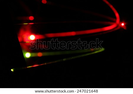 Two fiber optic cables, the upper red, the lower green, the lower in crisp focus.