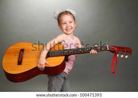 the little girl costs with a big guitar in hands, a look not in a lens, smiles, a double 3