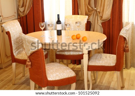 table, on a table the wine bottle, glasses and oranges, around cost chairs