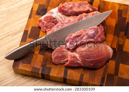 the cut meat and steel knife on a wooden chopping board