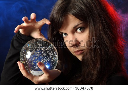 The beautiful girl with a crystal sphere, the sorcerer, against a dark background