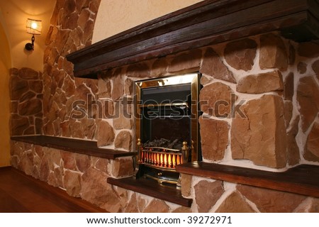 Spacious hall with a fireplace and a wall finished with a natural stone