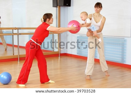 Mother and the child are engaged with the instructor in a sports hall
