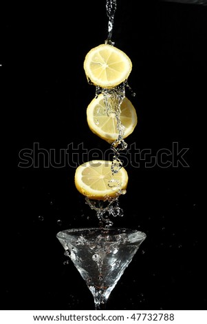 stock photo : The segments of fruit falling in a glass with a drink