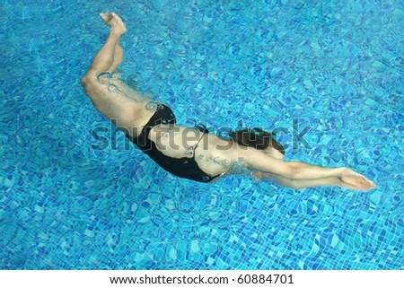 The woman floats under water in small pool
