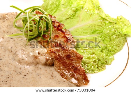 Well-done beefsteak with sauce and salad on a white plate