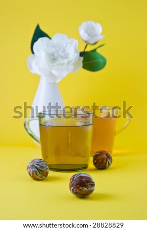 Green tea and vase with a white flower on a yellow background