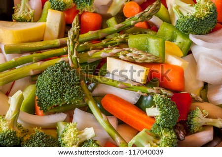 Miscellaneous fresh vegetables cut up in pieces ready for stir fry or saute. It includes carrots, broccoli, onions, asparagus, squash, and red and green pepper for healthy eating