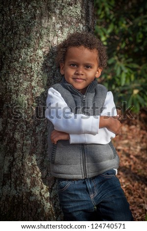 Young african-american boy standing by a tree for his portrait smiling for the camera.
