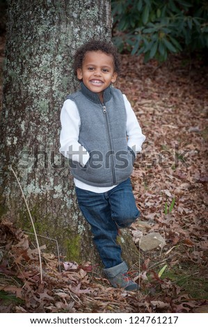 Young african-american boy standing by a tree for his portrait smiling for the camera.