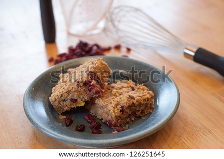 Homemade healthy breakfast oatmeal bars on a pottery plate. Bars are filled with dried fruit such as cranberries, apricots and dates for a fiber filled snack.