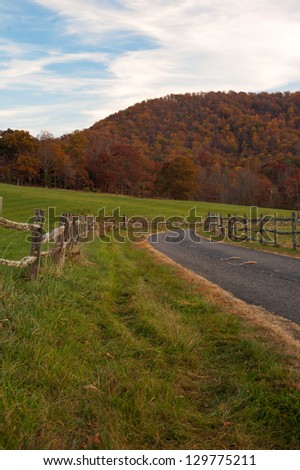 Old country road winding by a fence in the mountains of western North Carolina near the Blue Ridge Parkway during the autumn season.