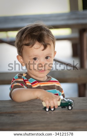 Little boy playing with toy truck looking at camera and smiling
