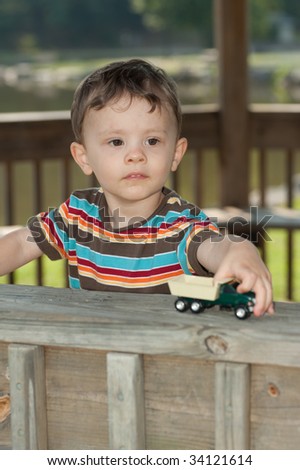 Little boy playing with toy truck looking at camera and smiling
